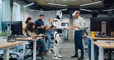 Çok ırklı bir grup araştırmacı yeni bir oluşumu test ediyor. VR kulaklık takan yetişkin bir erkek. Sanal gerçeklik gözlükleriyle insansı robotu çalıştırmaya çalışıyorum. Başarılı bir test. Herkes alkışlıyor..