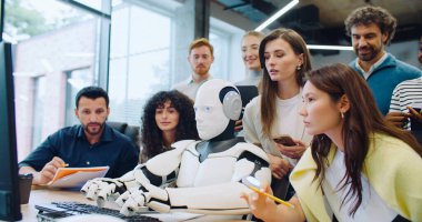 Çok ırklı zeki mühendislerden oluşan bir grup robotlarının metne girişine bakıyor. Program veya yazılımın doğru çalışıp çalışmadığını kontrol ediyorum. Otomatik aygıtın yanındaki kadın ses etkinleştirmesi ile yönetiliyor.