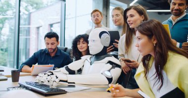 Akıllı mühendislerden oluşan çeşitli insanlar metne giren robotlarına bakıyor. Program veya yazılımın doğru çalışıp çalışmadığını kontrol ediyorum. Otomatik aygıtın yanındaki kadın ses etkinleştirmesi ile yönetiliyor.