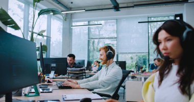 Masalarda oturan insanların önünde kamera kayıyor. Kafkasyalı işçiler yoğun çalışma saatleri boyunca odaklandı. Klavyede yazıyorum. Kulaklıkla çağrılara cevap veriyor. Mikrofonlarla konuşmak.