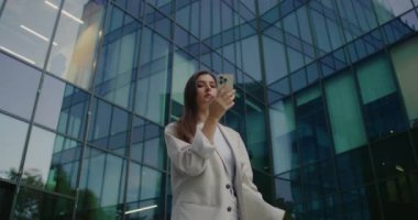 Kameralar beyaz bir kadının etrafında dolaşıyor. Beyaz takım elbiseli ve büyük çantalı bir kadın. Daktilo yazarken tek elle akıllı telefonu tutmak. Etrafı kolaçan ediyorum. İleti gönderiliyor.