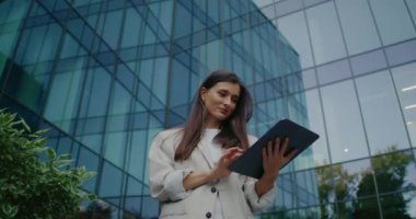 Kamera, cam duvarlı, uzun ofis merkezinin altında duran muhteşem kadından uzaklaşıyor. Kişisel tabletini kullanıyor. Boş zamanı internette gezinerek ya da haberleri izleyerek geçirmek. Şehirde akşam.