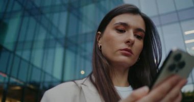 Akıllı telefonundan bildiri alan sevimli beyaz bir kadın. Dijital aygıt ekranındaki bilgiler kontrol ediliyor. Gülümserken tek parmağınla kısa mesaj yazıyorsun. Uzak iletişim.