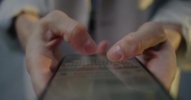 Akıllı telefon ekranının üstünden kamera görüntüsü. Dokunmatik ekranda iki başparmakla mesaj yazan kişi. Görünürdeki ileti giriş yapıyor ve klavye en altta. Uzak iletişim.