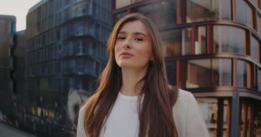 Büyük panoramik pencereli, modern binaların önünde duran çekici beyaz kadın. Resmi kıyafetler. En iyi manzara için poz vermek. Güzel manzaralı panoramik manzara.