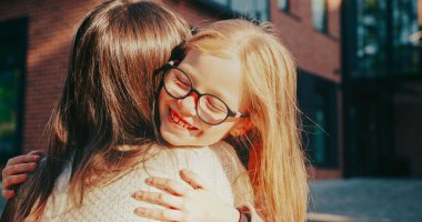 Annemin kollarını açarken oturduğu görüntüler. Küçük çocuk annesine doğru koşuyor. Sevilen bir aile üyesine sarılırken gülümsemek. Sonbahar akşamı. Arka planda bulanık okul.