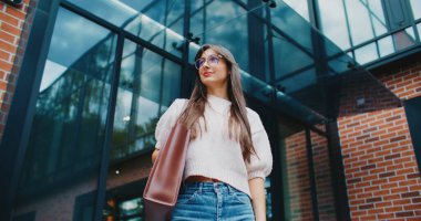 Kadın yüzünün aşağısından bak. Kız kameraya bakıyor ve gülümsüyor. Yönetici iş binasının önünde duruyor. Birini bekliyorum..