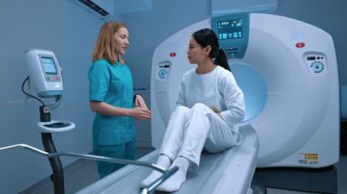 Profesyonel radyoloji doktorunun hastaya yakın durarak süreci açıkladığı modern bilgisayarlı tomografi odası. Bilgisayar tomografi tarayıcısı, klinikteki teşhis odasında biyopsi incelemesi..