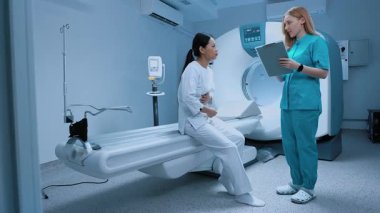 Modern klinikte biyopsi için röntgen bekleyen hasta. Tarayıcı masasında otururken doktoruna mide ağrısı şikayeti. MRI kapsülü ve klinikte yeni modern ekipmanlar.