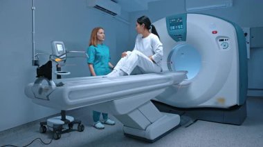 Radyolog, tıbbi merkezde manyetik rezonans görüntüleme makinesi kullanarak tanı koymadan önce hastaya danışıyor. Hasta tomografi işleminden önce doktordan tavsiye alıyor..