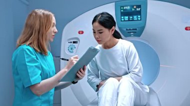 Doktor dosyayı tutuyor ve hasta semptomlarını not alıyor. Tomografide yatan hasta. MRI dolabı. Modern ekipmanlar özel klinikte. Doktor ameliyattan önce hastayla konuşuyor. MRI incelemesi.