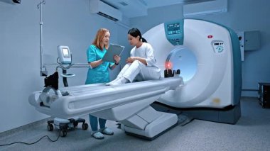 Doktor dosyayı tutuyor ve hasta semptomlarını not alıyor. Tomografide yatan hasta. Özel klinikteki modern donanımlı dolap. Doktor ameliyattan önce hastayla konuşuyor. MRI incelemesi.