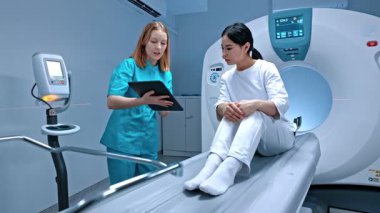 Doktor tableti tutuyor ve MR sonuçlarını gösteriyor. Hasta MRI kapsülünde yatıyor. MRI dolabı. Modern ekipmanlar özel klinikte. Doktor ameliyattan sonra hastayla konuşuyor. MRI incelemesi.