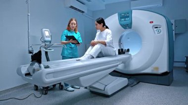 Doktor tableti tutuyor ve hastaya talimat veriyor. Tomografide yatan hasta. MRI dolabı. Modern ekipmanlar özel klinikte. Doktor ameliyattan önce hastayla konuşuyor. MRI incelemesi.