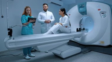 Beyaz önlüklü doktor MRI görüntüsünü inceliyor. Hasta MRI kapsülünde yatıyor. MRI dolabı. Modern ekipmanlar özel klinikte. Hemşire üniforması tablet taşıyor. MRI testi. Kısırlık prosedürü.