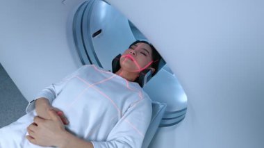 Beyaz giysili hasta manyetik rezonans görüntülemesinden geçiyor ve manyetik rezonans prosedürünü bekliyor. Bilgisayarlı tomografi tarama yatağı. Biyopsi röntgen incelemesi prosedürü.