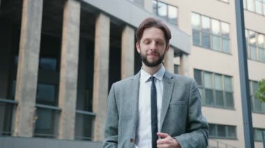 Gözlük takan, kameraya bakan, başını sallayan ve göz kırpan beyaz adamın portresi. İş adamı, banka çalışanı kentsel arka planda duran modern ofis. Erkek resmi takımı.