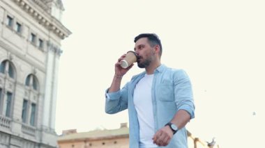 Sokakta yürürken günlük giysiler içinde kahve içen mutlu beyaz adam. Eski şehir caddesine bakıyorum. Yavaşlıyorum. Yaşam biçimi