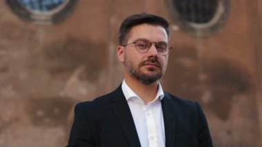 Gözlüklü beyaz erkek portresi başını çeviriyor ve kameraya bakıyor. Resmi kıyafetli başarılı orta yaşlı sakallı adam. Takım elbiseli işadamlarına yaklaş.