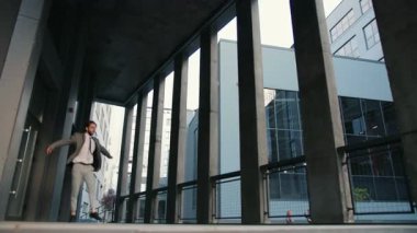 Profesyonel genç dansçı ofis binasının yakınında bale hareketleri yapıyor. Takım elbiseli bir erkek. Morden bölgesi. Atletik insanlar.