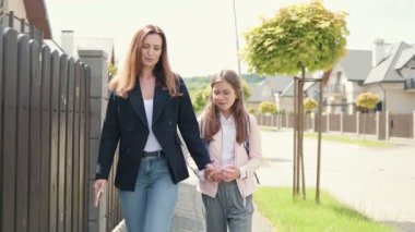 Ceketli ve kotlu güzel bir annenin portresi. Kızının elini tutuyor ve yürüyor. Orta yaşlı bir kadın okuldan dönerken küçük çocuğuyla konuşuyor. Aile kavgası kavramı.