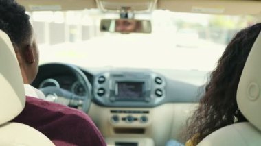 Afro-Amerikan erkek ve kadın sürücü arabasının arka koltuğu. İnsanlar müzik dinliyor, gülümsüyor ve konuşuyor. Kahve içen bir adam, gözlüklü bir kadın. Mutlu bir çift. Mordern arabası..