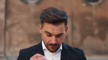 Yakın çekimde, gözlük takan, sakallı, beyaz, yakışıklı genç bir adamın sinematik portresi. Erkek ciddi görünüyor. Akıllı takım elbiseli adam kameraya bakıyor..