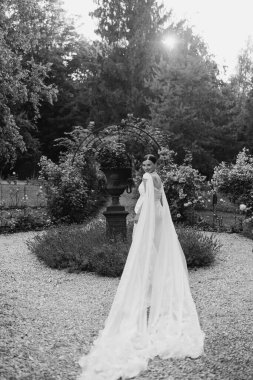 Büyüleyici bir gelin çiçeklerle ve yeşilliklerle dolu güzel bir bahçede zarifçe yürür.