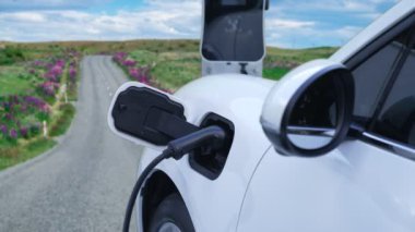 Tepe yolundaki şarj istasyonunda elektrikli arabanın çevresel farkındalığı için yenilikçi bir kavram. EV araba temiz çevre için yenilenebilir enerjiden güç alıyor.
