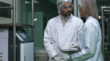 Kimyasal ve biyomedikal deney laboratuarında çalışan profesyonel üniformalı iki bilim adamı.