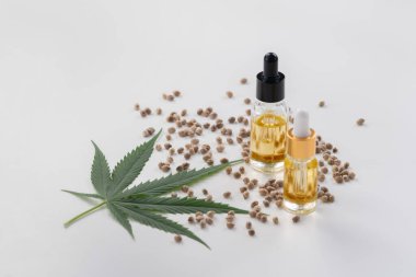 Şişede CBD yağı, damlacık kapağı, sativa yeşil kenevir ve kenevir tohumu bulunan yasallaştırılmış marihuana özellikleri. Copyspace ve reklam için esrar ürünü.