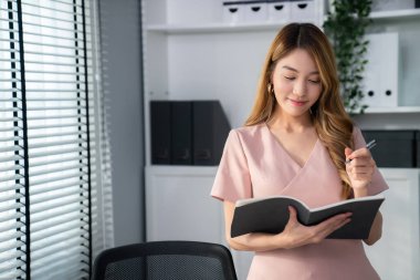 Young competent office lady, intern, secretary holding a log in office room. Concept of various career for office working. Concept of diverse office careers.