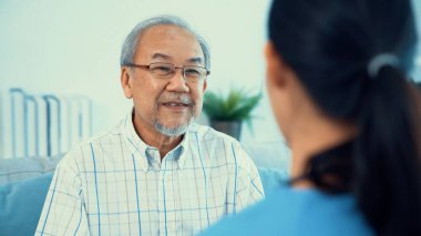 A young female doctor inquires about personal information of a contented senior at home. Medical care for the elderly, elderly illness, and nursing homes, home care.