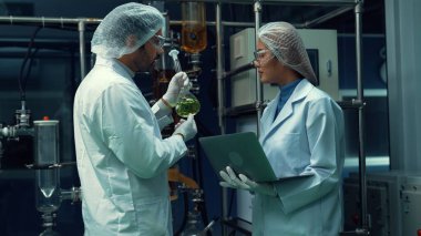 Kimyasal ve biyomedikal deney laboratuarında çalışan profesyonel üniformalı iki bilim adamı.