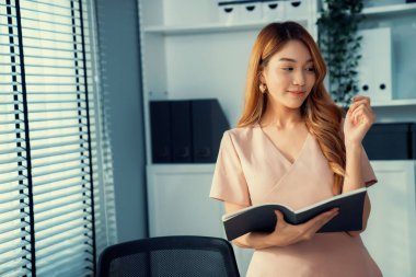Young competent office lady, intern, secretary holding a log in office room. Concept of various career for office working. Concept of diverse office careers.