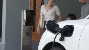 İlerici ebeveynler kızlarını okuldan alırken elektrikli araba ve yenilenebilir enerji kavramını kullandılar, evdeki EV otomobil için şarj istasyonu. Alternatif eko taşımacılığı.