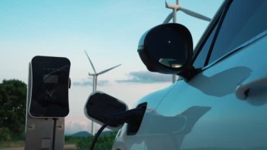 Çevreyi korumak için rüzgar türbininden yeşil ve yenilenebilir enerjiyle çalışan şarj istasyonunda şarj edilen gelişmiş gelecek enerji altyapısı konsepti.