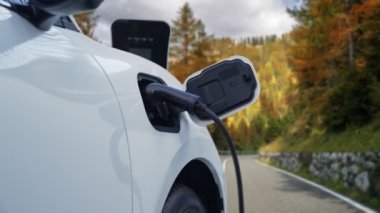 Tepe yolundaki şarj istasyonunda elektrikli arabanın çevresel farkındalığı için yenilikçi bir kavram. EV araba temiz çevre için yenilenebilir enerjiden güç alıyor.