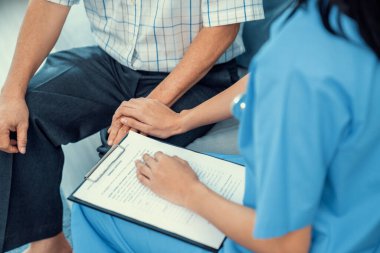 Senior man feeling contented as his caregiver provides him with good news about his health at medical consultation.