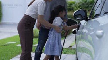 Elektrikli araç şarj istasyonu olan, sağlıklı ve temiz bir çevreyi teşvik eden yenilikçi bir aile kavramı. Sürdürülebilir, temiz enerji teknolojisiyle çalışan elektrikli araç..
