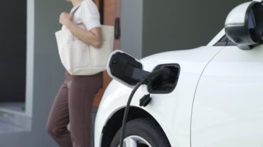 Bir kadın evinde elektrikli araç şarj aletinin fişini çekiyor. İlerici bir yaşam tarzında elektrikli araçların kullanımı, temiz ve sağlıklı bir çevreye katkıda bulunur..