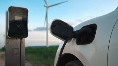 Çevreyi korumak için rüzgar türbininden yeşil ve yenilenebilir enerjiyle çalışan şarj istasyonunda şarj edilen gelişmiş gelecek enerji altyapısı konsepti.