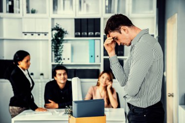 Depressed and disappointed employee packing his belongings after being fired for not being competent. Gossiped by his colleagues behind his back. Layoff due to economic depression.