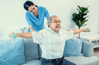 Contented senior patient doing physical therapy with the help of his caregiver. Senior physical therapy, physiotherapy treatment, nursing home for the elderly