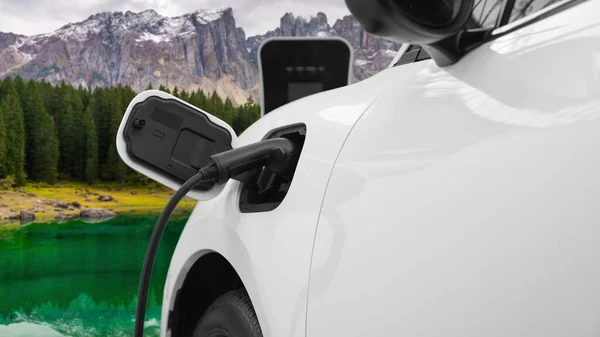 電気発生器ドライブによるエネルギー持続可能な車の電源 プログレッシブ旅行の概念のための山の背景と充電ステーションでバッテリーを充電します クリーン環境のシンボルとして自然界のEv車 — ストック写真
