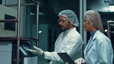 Kimyasal ve biyomedikal deney laboratuarında çalışan profesyonel üniformalı iki bilim adamı.