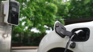 Yakın çekim yenilikçi modern ulaşım konsepti, elektrikli araba şarj istasyonunda gökyüzünden yansıyan yüksek detay ile şarj ediliyor. Yenilenebilir enerji tarafından kullanılan çevre dostu elektrikli araç.