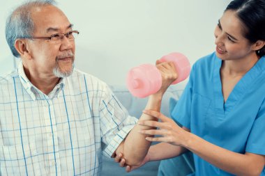 Contented senior patient doing physical therapy with the help of his caregiver. Senior physical therapy, physiotherapy treatment, nursing home for the elderly