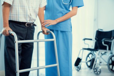 Physiotherapist assists contented senior man on folding walker. Recuperation for elderly, seniors care, nursing home.