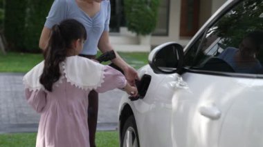 Evde şarj edilen elektrikli bir araçla okuldan yeni dönen anne ve kızın ilerici yaşam tarzı. Elektrikli araç, sürdürülebilir temiz enerjiyle çalışıyor..